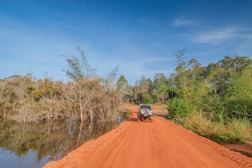 view of a 4wd. truck parking on dirt road around with green grass, swamp and blue sky background, adventure in Thung Salang Luang National Park, Phetchabun, Thailand.
