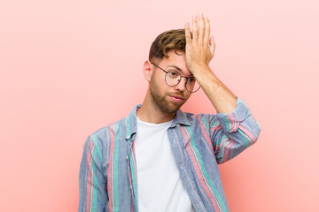young man raising palm to forehead thinking oops, after making a stupid mistake or remembering,...