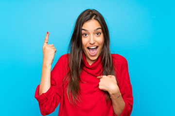 Young woman with red sweater over isolated blue background with surprise facial expression