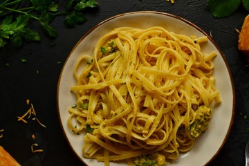 Spaghetti in a beautiful plate on a dark background. Appetizing pasta with broccoli. Noodles with cream and cheese. Homemade noodles.