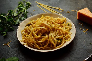 Spaghetti in a beautiful plate on a dark background. Appetizing pasta with broccoli. Noodles with cream and cheese. Homemade noodles.