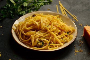 Spaghetti in a beautiful plate on a dark background. Appetizing pasta with broccoli. Noodles with cream and cheese. Homemade noodles.