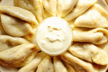 Dumplings in a beautiful plate. Dumplings on a wooden background. Wooden table background with autumn leaves. Appetizing little pie with filling. Traditional homemade food.