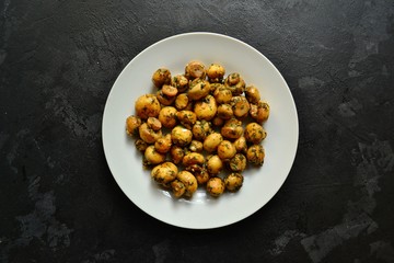 Fragrant fried champignons. Grilled mushrooms in a beautiful plate. Food isolated on a dark concrete background.