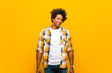 young black man looking happy and friendly, smiling and winking an eye at you with a positive...
