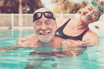 couple of two seniors hugged in the water of swimming pool - active man and woman doing exercise...