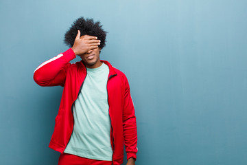 young black sports man covering eyes with one hand feeling scared or anxious, wondering or blindly...