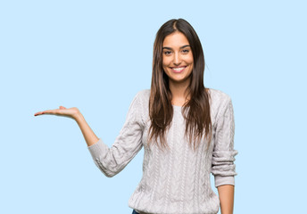 Young hispanic brunette woman holding copyspace imaginary on the palm to insert an ad over isolated...