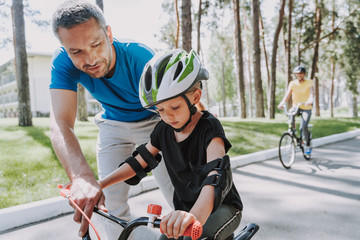 Smiling father teaching his daughter to ride a bicycle