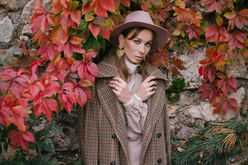 Woman in fashion clothes posing in beautiful yard.