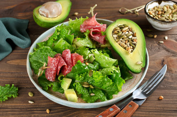 Salad with avocado, salami, pine nuts, pumpkin seeds and sunflower seeds