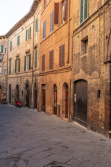 Fototapeta na wymiar An empty back street of Siena, with a buildings that curve into the distance
