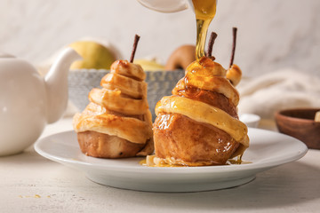 Pouring of honey onto sweet cooked pears on plate