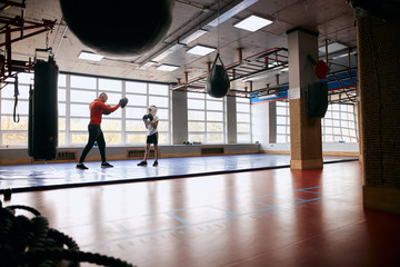 young man and his song exercising at sport club, full length photo