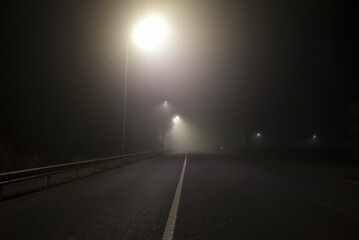 The thick fog above the asphalt road in the night outside the city