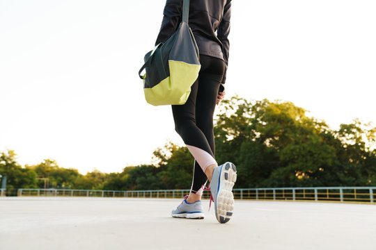 Cropped image of woman walking with sport bag for workout outdoors