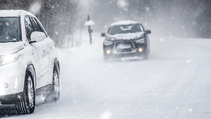 Fototapeta na wymiar Winter road in beatiful forest. Snow calamity or blizzard. Fast cars on snowy roads in storm.