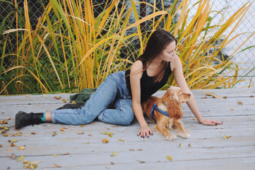 Girl with her dog, English Cocker Spaniel, sitting on the bench near the lake