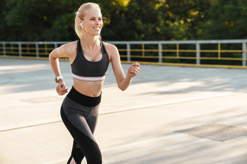 Fototapeta na wymiar Image of caucasian fitness woman wearing tracksuit running outdoors