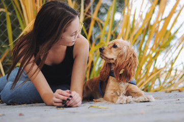 Girl with her dog, English Cocker Spaniel, sitting on the bench near the lake
