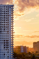 Apartment building under construction at sunset, copy space