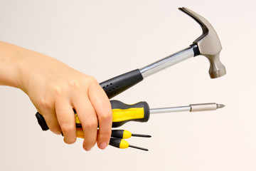 Hammer and screwdriver in hand on a white background. Outstretched construction tools