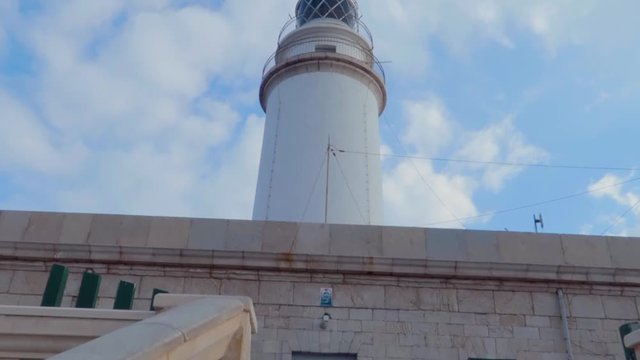 A low angle track view of a spectacular Cap de Formentor lighthouse's stairs of red stones and fence with shining blue sky, on the northernmost point of the Balaeric Island Mallorca in Spain.