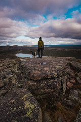 Woman and dog on rocky summit with lake view