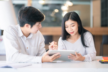 Obraz premium Young Asian couple or college student using digital tablet and laptop computer notebook work together at coffee shop or university campus.