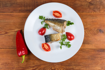 Top view of baked mackerel slices with greens and tomatoes