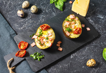 Keto diet: Avocado with ham, quail eggs, cheese on stone background