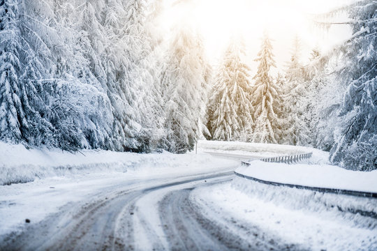 Winter beautiful snowy road snow or landscape forest and trees covered with snow. Yellow sun shine lights in background.