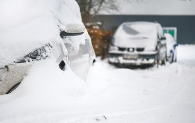 Cars covered with heavy white snow on calamity road. Winter car concept in storm or blizzard.