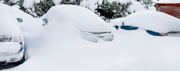 Cars covered with heavy white snow on calamity road. Winter car concept in storm or blizzard.