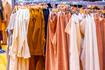 Clothing rack with colorful autumn women's clothes (skirts, raincoats, trench coats) in the modern fashion store.