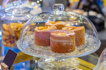 Delicious cakes in a Glass Cake Stand on the cafe counter.  Dessert buffet, storage