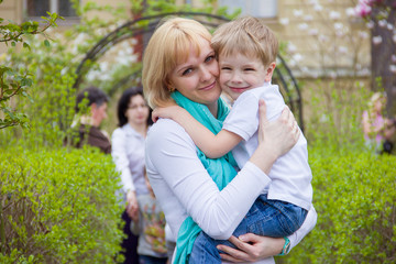 Naklejka na ściany i meble happy mom and son cuddling in the park, family day, vivid emotions