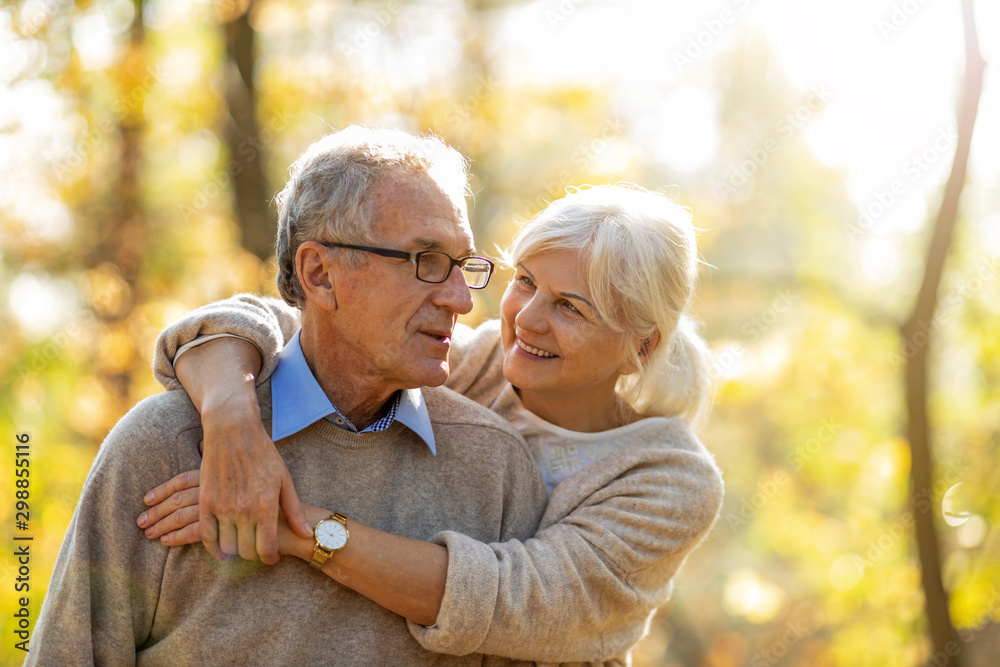 Poster Elderly couple embracing in autumn park 