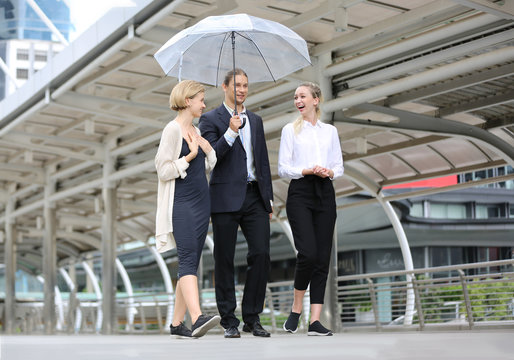 business man holding umbrella walk on footbridge with business women