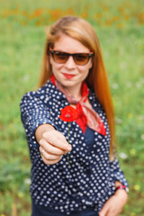 Young woman holding a red flower in the field