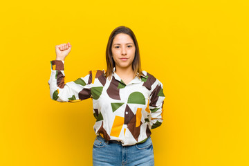 latin american woman feeling serious, strong and rebellious, raising fist up, protesting or...