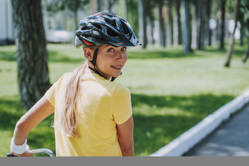 Beautiful woman in safety helmet riding bicycle outdoors