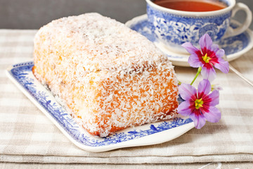 Coconut cake and cup of tea on the table.