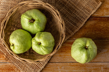 Guava in a wooden basket placed on a wooden floor