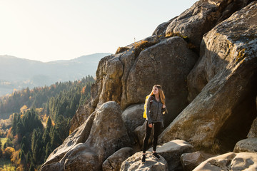 Outdoor recreation. Girl in sportswear with backpack stands on stone mountain.