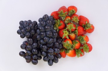 Dark blue grapes and strawberries on white background.