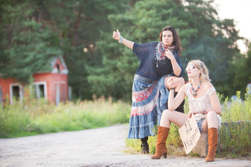 Fototapeta premium Two beautiful women by the road travel hitchhiking. Free transport.