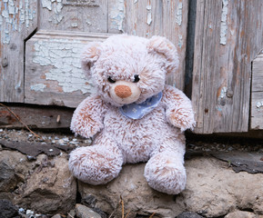 little teddy bear sits on the doorstep near an old door with cracked paint