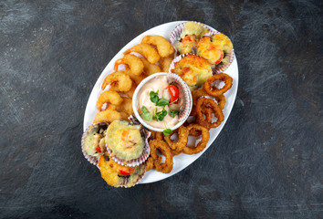 PERUVIAN FOOD. Piqueo caliente. Hot seafood platter fried shrimps, squid rings and baked scallops with sauce