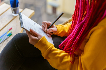 Unrecognizable person, girl artist, illustrator draws in notebook, makes sketch. Close-up of woman...
